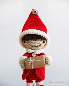 a crocheted doll holding a brown box