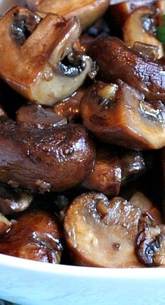 a white bowl filled with mushrooms on top of a table