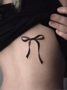 a woman's stomach with a bow tattoo on it