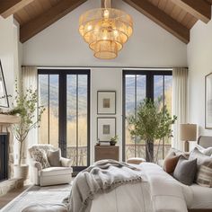 a large bed sitting in a bedroom under a chandelier next to a fireplace