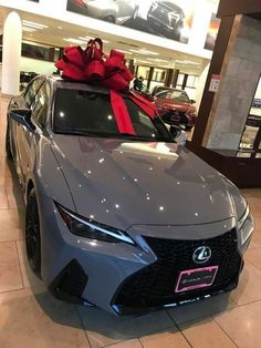 a gray car with a red bow on it's hood in a showroom