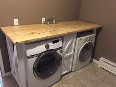 a washer and dryer in a small room with a wooden counter top above it