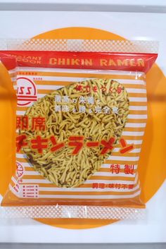 a package of noodles with chinese writing on the front and in the back, sitting on top of a yellow plate