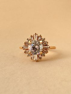 an engagement ring with a center stone surrounded by smaller stones, on a beige background