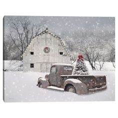 an old truck with a christmas tree on the back parked in front of a barn