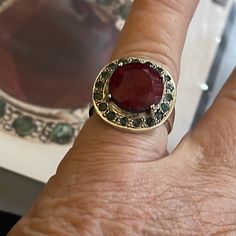 a woman's hand with a ring on it that has a red stone in the middle