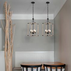 two chandeliers hanging from the ceiling above a dining room table with four chairs