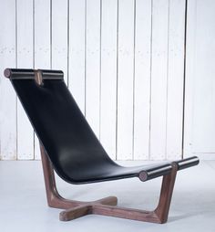 a brown leather lounge chair sitting on top of a white floor next to a wooden wall