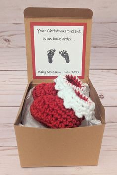 a red and white crocheted hat in a cardboard box with a card saying your christmas present is an adorable order