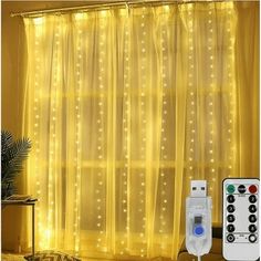 an image of a bedroom setting with lights on the curtain and remote control in front