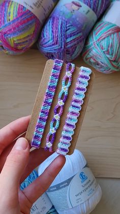 a person is holding up some yarn on a piece of cardboard with scissors in front of them