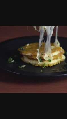 pancakes with cheese being drizzled on them and topped with parmesan