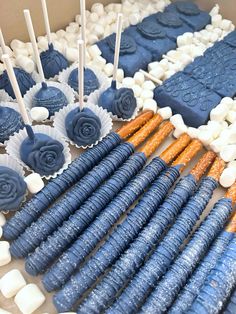 blue and white desserts are arranged on a table with candy sticks in the shape of roses