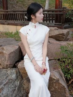 This is a pure white cheongsam with a lining made of cotton and fabric composed of 46% tencel and 54% Rayon. It features red jade buttons. There are two length options for the dress: 120cm and 130cm. It has 13 pairs of handmade button closures and no zipper at the back. The fabric does not have any elasticity. Size Chart: S: Shoulder width-36cm, Chest-84cm, Waist-68cm, Hip-86cm M: Shoulder width-37cm, Chest-88cm, Waist-72cm, Hip-90cm L: Shoulder width-38cm, Chest-92cm, Waist-76cm, Hip-94cm XL: S Fitted White Cheongsam For Summer, Traditional White Cheongsam For Spring, White Summer Cheongsam With Stand Collar, Qipao Gown, White Cheongsam, Cheongsam Traditional, Traditional White Summer Cheongsam, Traditional White Long Sleeve Cheongsam, Cheongsam Top