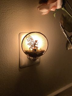 a light that is on the wall next to a vase with some flowers in it