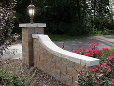 a stone bench sitting in the middle of a flower garden next to a lamp post