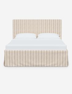 an upholstered bed with white sheets and beige pinstripe bedspread