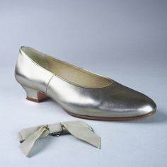 a pair of silver shoes with a white bow