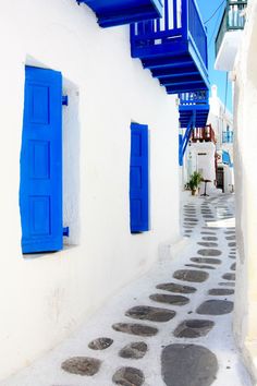 an alley way with blue shutters and stone walkway leading to the second story building