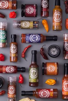 hot sauces and other condiments are arranged on a gray surface, including peppers