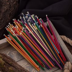 many different colored straws are in a wooden box on the ground next to some rope