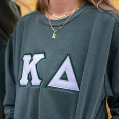 a woman wearing a sweatshirt with the letters k and a triangle on it's chest