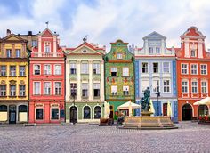 many colorful buildings line the street in front of a fountain