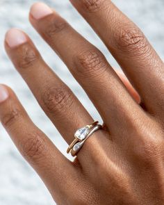 a woman's hand with a gold and white ring on her left hand, wearing a wedding band