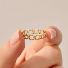 a woman's hand holding a gold ring with diamonds