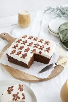 a piece of cake with white frosting on a wooden platter next to other plates and utensils