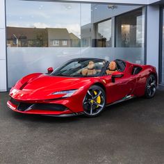 a red sports car is parked in front of a building with glass doors and windows