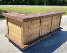 a wooden box sitting in the middle of a parking lot next to a grass field