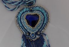 a blue and white beaded necklace with a heart hanging from it's side