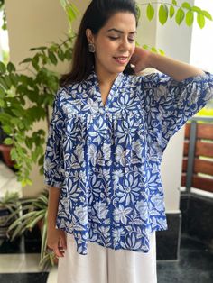 Blue & White unique Jaipuri Cotton Print handmade top,features a mandarin frill collar,3/4th puff sleeves and mid length. extremely stylish and comfortable for every occasion,looks amazing with shorts or denims.This blouse is comfort & bohemian fit, while picking size you can size down as well ,refer to the size chart or drop us a message if you need assistance. the volume sleeves add a stylish touch and the unique hand block print is eye catching Model is wearing size S Also available in  S,M,L Casual Blue Block Print Tops, Traditional Block Print Tunic Top, Traditional Long Sleeve Ikat Print Top, Blue Floral Print Tunic Kurta, Jaipuri Print, Multicolor Block Print Long-sleeve Blouse, Bohemian Top, Volume Sleeves, Frill Collar