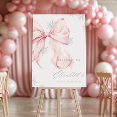 a welcome sign for a baby shower with pink and white balloons on the wall behind it