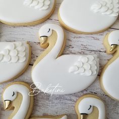 decorated cookies in the shape of swans on a wooden table with white frosting and gold trimmings