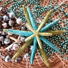 a basket filled with ornaments and beads on top of a wooden table covered in blue and green decorations