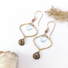 Immerse yourself in the whimsical charm of our Boho Aurora Earrings. These earrings are a celebration of bohemian elegance and the radiant palette of autumn's dawn. Handcrafted with care, each earring boasts unique handmade and textured components that reflect the individuality found in the natural world. Delicate wire-wrapped pink tourmaline gems crown the top, adding a touch of delicate femininity that's reminiscent of the season's blossoms. Inside the components, nestled like secrets waiting Bohemian Sterling Silver Briolette Earrings, Sterling Silver Bohemian Briolette Earrings, Nature-inspired Dangle Gemstone Earrings, Nature-inspired Gemstone Dangle Earrings, Bohemian Gold Gemstone Earrings, Fusion Style Teardrop Earrings With Ear Wire, Handmade Fusion Style Chandelier Drop Earrings, Handmade Fusion Chandelier Drop Earrings, Bohemian Briolette Nickel-free Jewelry