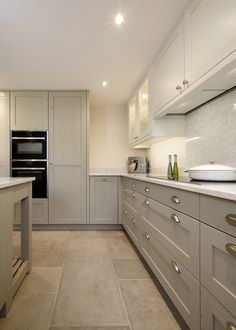 a large kitchen with white cabinets and marble counter tops, along with an oven in the center