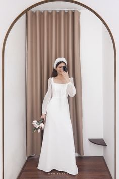 a woman in a white dress taking a selfie with her cell phone and flowers