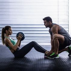 a man and woman doing squats on the floor with a medicine ball in front of them