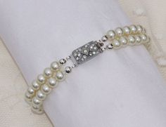 "A stunning vintage bracelet made during the art deco era. This is a two strand bracelet made with very soft white colored glass pearls. The pearls are in wonderful vintage condition and have a great luster and shine! Pearls are 6mm in size and connect to a paved, rhodium plated tongue and groove clasp. The tongue and groove clasp does have two small silver push points on the side, which is not shown in the photos. The pearls have been re-strung onto new, strong silk cording so you can ensure it Pearl Bracelet Silver, Authentic Art, Multi Strand Bracelet, Silk Cord, Vintage Bracelet, White Bridal, Strand Bracelet, Bracelet Silver, Vintage Bracelets