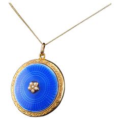 We are delighted to offer this splendid late Victorian/early Edwardian blue enamel pendant necklace made c.1900 in 9ct solid gold. Striking and distinguished from contemporary pieces, this pendant necklace features a wonderful blue enamel guilloche design in the centre with a fine engine-turned pattern underneath. The blue enamel has a gorgeous hue which is elegant in the shadows, yet presents more vibrancy when exposed to sunlight with its glossy surface. In addition to its rich enamelling, the centre is embellished with a cluster of seed pearls as if to form a flower. A wonderful accent and touch to the overall piece making it a lovely and distinguished piece of antique jewellery. The reverse side presents a locket with a glass panel in which a photo of a loved one may be placed within. Yellow Gold Enamel Medallion Necklace, Yellow Gold Enamel Oval Pendant Necklaces, Victorian Enamel Locket Jewelry, Antique Yellow Gold Necklace With Cabochon, Antique Enamel Necklace For Wedding, Antique Enamel Necklaces For Wedding, Blue Enamel Locket Jewelry, Blue Oval Enamel Necklace, Luxury Blue Locket Jewelry