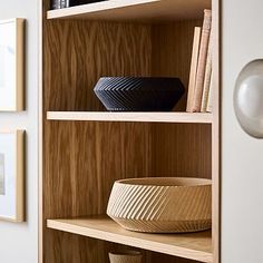 a wooden shelf filled with books and vases on top of it's shelves