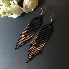 black and gold beaded earrings next to white flowers