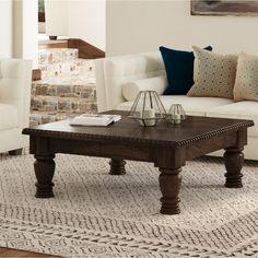 a living room with two couches, a coffee table and pillows on the floor