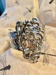 Art Nouveau style cuff.  Magnificent hand crafted Alphonza Mucha style Lady Cuff. From MyElegantThings Design Studio"  Antique silver plated over brass cuff. Engraved cuff with gorgeous flowers and vines and leaves. Vintage style very limited edition Cuff is an engraved and gorgeous garden piece. 1 inch width. Woman piece is 1-1/2 inches. Gorgeous and what a statement. Unique Silver Cuff Bracelet, Artistic Silver Cuff Bracelet, Handmade Antique Silver Cuff Bracelet For Wedding, Ornate Silver Cuff Bracelet, Artistic Silver Cuff Bracelet Bangle, Artistic Silver Cuff Bangle Bracelet, Artistic Silver Bangle Cuff Bracelet, Adjustable Silver Cuff Bracelet Wearable Art, Handmade Silver Cuff Bracelet As Gift