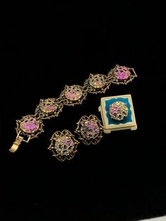 "This color changing set is oh so pretty; each round 'stone' in the bracelet and clip earrings is set in a decorative brass colored metal which measures 1 1/2\" long by 1 1/2\" wide; the ring is set in a simple setting of the same colored metal; depending on the angle, the colors reflect blue, pink, green, yellow or orange; bracelet is 7 1/2\" long, and each 'stone' is 7/8\" round; dress up or down." Formal Metal Clip-on Jewelry, Vintage Round Clip-on Jewelry, Round Vintage Clip-on Jewelry, Antique Jeweled Jewelry, Elegant Iridescent Bracelet Jewelry, Handmade Iridescent Bracelet, Adjustable Costume Jewelry Sets With Round Shape, Gold Bohemian Clip-on Jewelry, Elegant Multicolor Filigree Jewelry