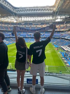 two young people holding up a scarf at a soccer game in a stadium with blue seats