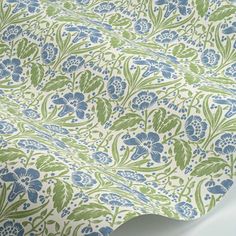 a blue and green flowered wallpaper with leaves on the bottom half of it